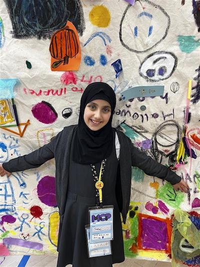 Member of Children's Parliament stands in front of their artwork. Anti racism education (Children's Parliament 2024)